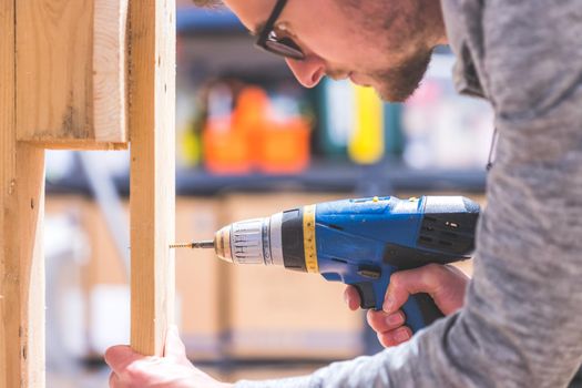 Do it yourself home handyman is using a cordless screwdriver for screwing