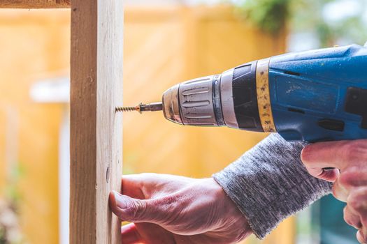 Do it yourself home handyman is using a cordless screwdriver for screwing