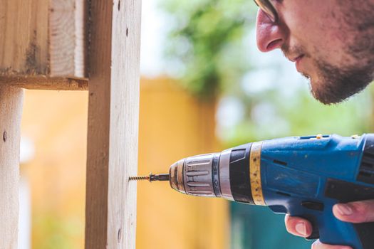 Do it yourself home handyman is using a cordless screwdriver for screwing