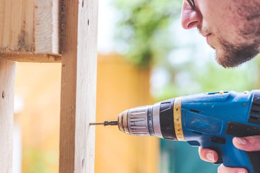 Do it yourself home handyman is using a cordless screwdriver for screwing