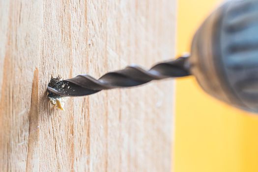 Do it yourself home handyman is using a drill for drilling wood