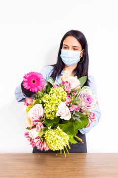 Cute woman florist is making a bouquet of roses, hydrangeas and alstroemerias