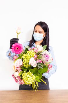 Cute woman florist is making a bouquet of roses, hydrangeas and alstroemerias