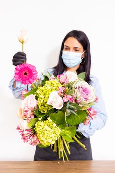 Cute woman florist is making a bouquet of roses, hydrangeas and alstroemerias