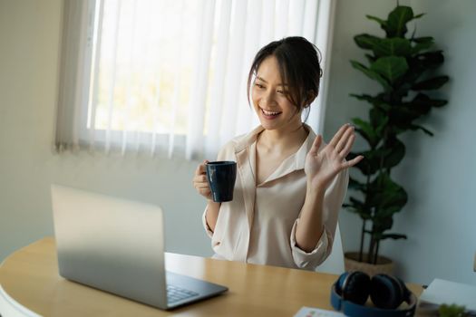 Joyful businesswoman sitting at desk looking at laptop screen talking with friend make informal video call.