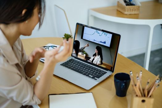 Rear view of female employee meeting via video call with employee brief the stock market chart