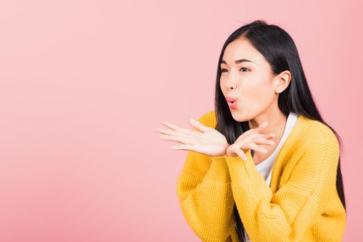 Asian happy portrait beautiful cute young woman teen standing blowing kiss air something on palm hands expresses her love looking to side away studio shot isolated on pink background with copy space