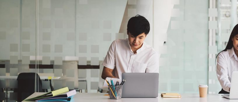 Two business people working with laptop computer at modern office.