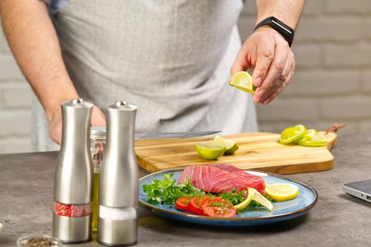 Cooking with notebook tuna steak in home kitchen. Online cooking recipe concept, fish cooking at home. lifestyle, healthy eating, cooking and dieting concept.