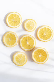 Sliced lemon on a white background . Lemon layout. Sliced fruit. Yellow color. White background. Light and shadow. Citrus. Healthy food. Copy space