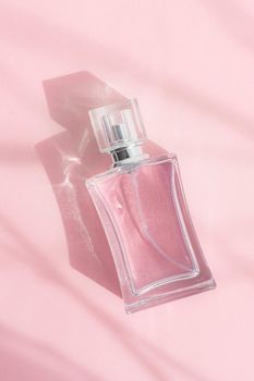 A bottle of perfume on a pink background . Pink perfume. Smell. Aromatherapy. An article with a place for the text about the choice of perfume fragrance. Light and shadows. Naturalness . Copy space