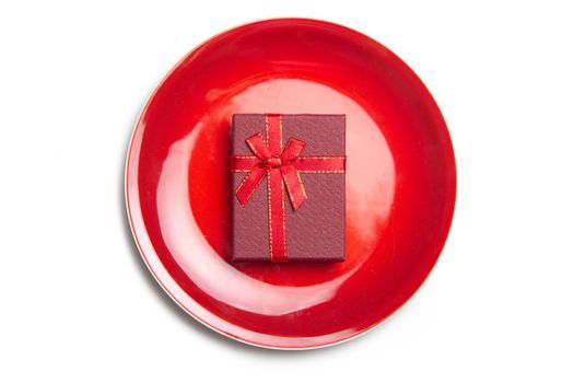 Red gift on a plate . Serving a festive table. New Year and Christmas. Gift wrapping . copy space