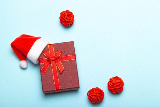 Red gift on a blue background . A gift with a Santa hat. Christmas and new year. A gift for the holiday. Red gift wrap.