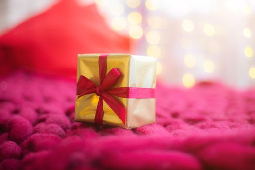 Gift on a blanket new year . a festive atmosphere. Article about choosing a gift. Bokeh lights. Garland defocus. Gift on the background of a garland . copy space