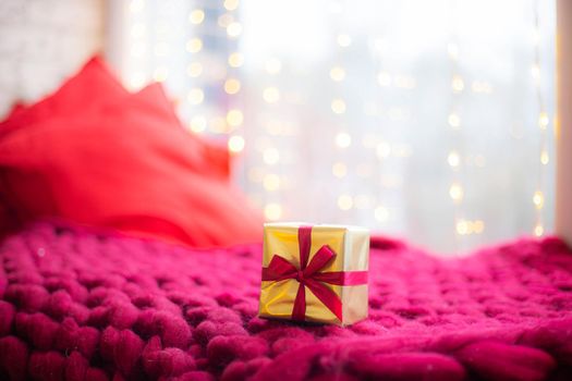 Gift on a blanket new year . a festive atmosphere. Article about choosing a gift. Bokeh lights. Garland defocus. Gift on the background of a garland . copy space