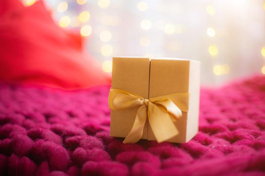 Gift on a blanket new year . a festive atmosphere. Article about choosing a gift. Bokeh lights. Garland defocus. Gift on the background of a garland . copy space