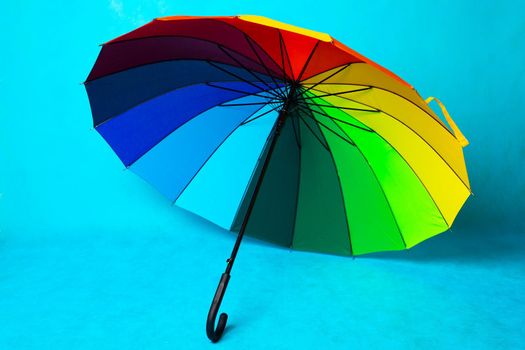 Colored umbrella on a blue background . Bright umbrella. Copy space. Article about the protection from the rain.