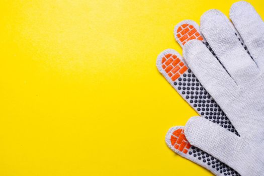 Gardening gloves on a yellow background . Work gloves on a yellow background. Yellow background. An article about dirty work. Hand protection. Copy space
