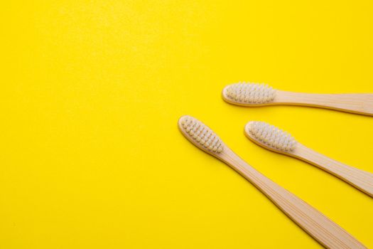Bamboo brush on a yellow background. No plastic. Ecology. Taking care of the world around you. Toothbrush. Clean teeth. Yellow background. Copy space. An article about taking care of the environment.
