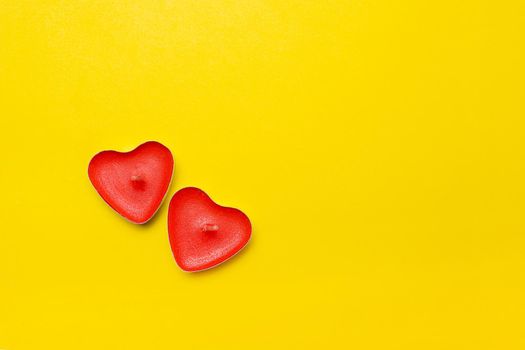 Candles in the form of hearts on a yellow background . Red candles. Red hearts. Yellow background. Copy space. Valentine's Day. Holiday. An article about celebrating Valentine's Day.. An article about love.