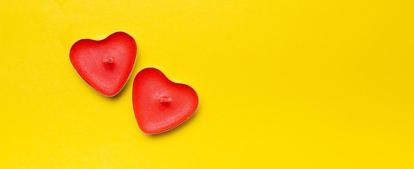 Candles in the form of hearts on a yellow background . Red candles. Red hearts. Yellow background. Copy space. Valentine's Day. Holiday. An article about celebrating Valentine's Day.. An article about love.