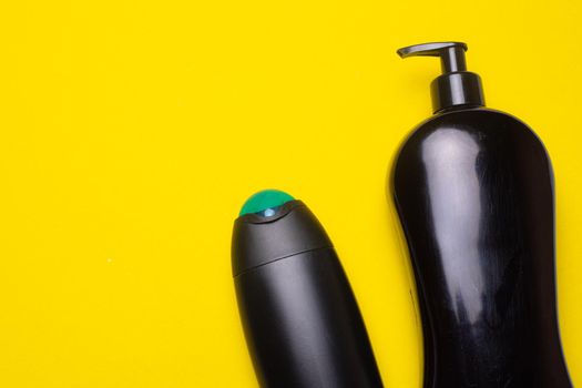 Black shampoo on the background of copyspace. A bottle of shampoo. Yellow background. Article about the beauty industry. Shampoo on a yellow background