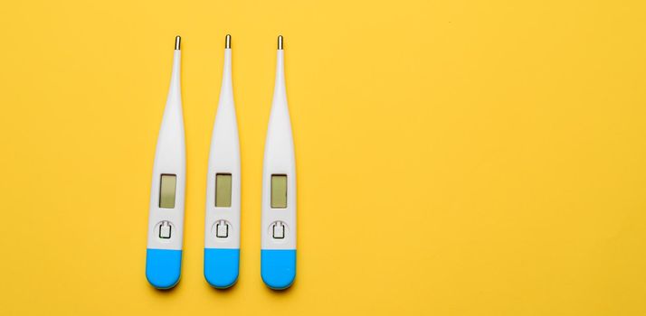 Electronic thermometers . Electronic thermometer on a yellow background. Temperature measurement. Safe thermometer. Modern medical equipment. Science and medicine. Article about safe thermometers. Technologies. Yellow background . Copy space