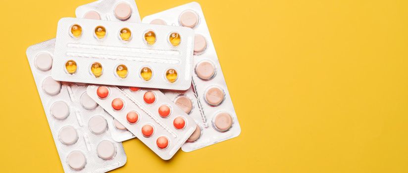 A pile of pills on a yellow background . Treatment and prevention. Article about the purpose of treatment. A cure for the disease. Pills in a blister. Lots of medicine. Yellow background. Copy space