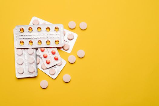 A pile of pills on a yellow background . Treatment and prevention. Article about the purpose of treatment. A cure for the disease. Pills in a blister. Lots of medicine. Yellow background. Copy space