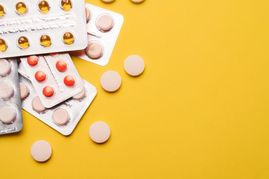A pile of pills on a yellow background . Treatment and prevention. Article about the purpose of treatment. A cure for the disease. Pills in a blister. Lots of medicine. Yellow background. Copy space