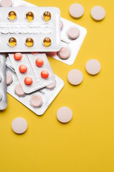 A pile of pills on a yellow background . Treatment and prevention. Article about the purpose of treatment. A cure for the disease. Pills in a blister. Lots of medicine. Yellow background. Copy space