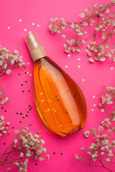 Suntan oil on a pink background. Uniform tan. A bottle of suntan oil . Protection of the skin. Vacation. Article about the choice of tanning products and tanning products. Pink background. White flowers. Beauty. Copy space