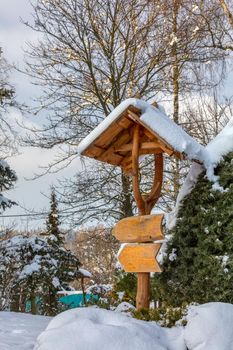 beautiful wooden signpost in winter garden covered with fresh snow
