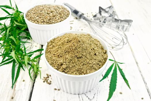 Flour and hemp grain in bowls, mixer and cookie cutters, cannabis leaves on the background of wooden boards