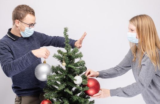 Couple trying to maintain social distancing while decorating Christmas tree wearing mask