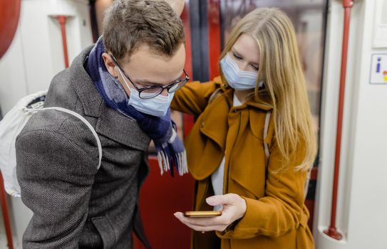 People using phone in train wearing covid-19 face mask during their commute