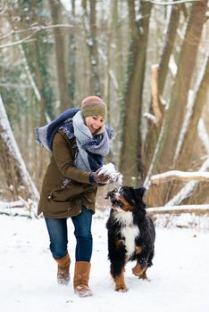 Woman playing with her dog in the snow on a winter day