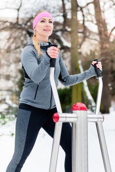 Young woman training her legs on fitness path at winter day in the park