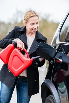 Woman filling car up with gas from the reserve canister happy she has one
