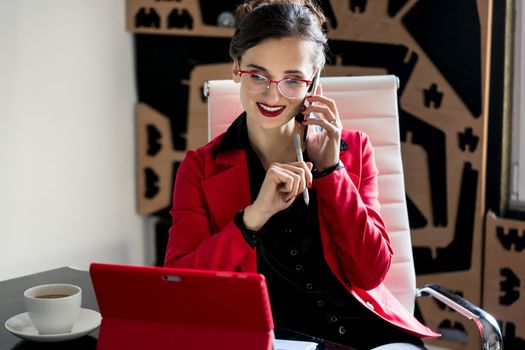 Businesswoman working with her computer while being on the phone talking to a customer