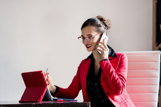 Businesswoman working with her computer while being on the phone talking to a customer