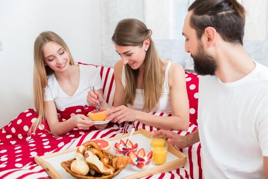 Family of three having its breakfast together in bed