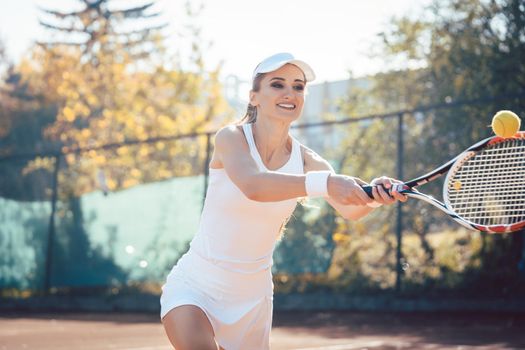 Woman playing tennis on court hitting the ball