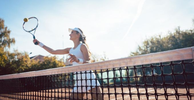 Woman getting a ball close to net on the tennis court