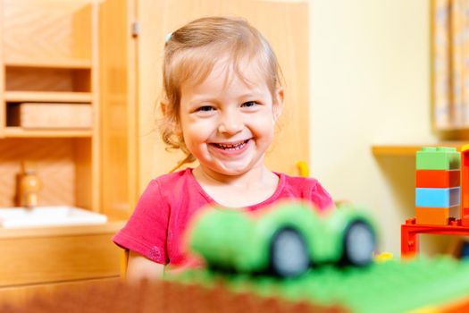 Little girl playing with a toy car in kindergarten