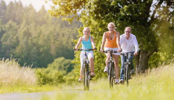 Parents and daughter have bicycle tour on country lane