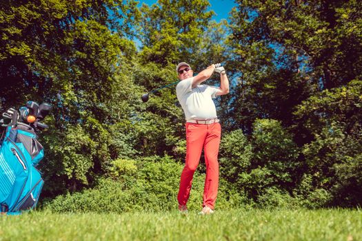 Golf player at the tee hitting ball far, tele shot