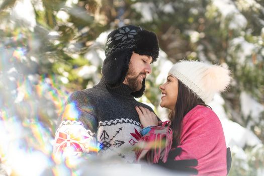 Portrait of happy couple looking at each other and smiling in winter forest to come spending quality time
