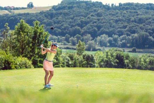 Beautiful woman playing golf on open course