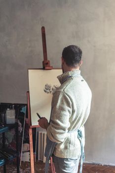 Rear view of male artist sketching on easel board